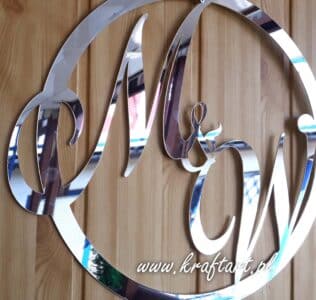 Srebrna dekoracja ślubna z inicjałami na tle paneli