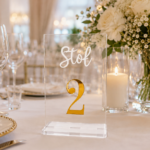 Transparentny numerek na stół weselny ze złotą cyfrą glamour na eleganckim stole weselnym
